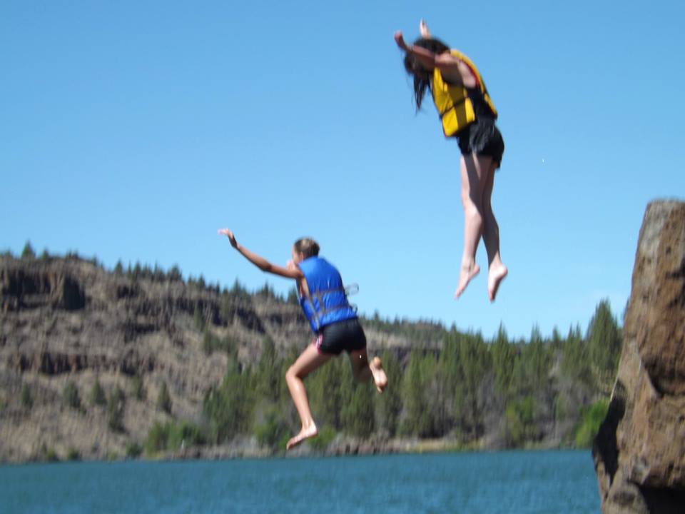 Two girls jumping off roacks.