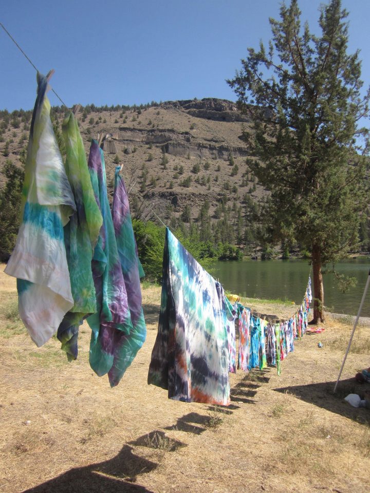 Tye dyeone a clothes line, infront of a lake.